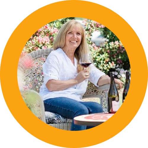 Debbie Woodwood of Privato Vineyard and Winery smiling while enjoying a glass of wine outside
