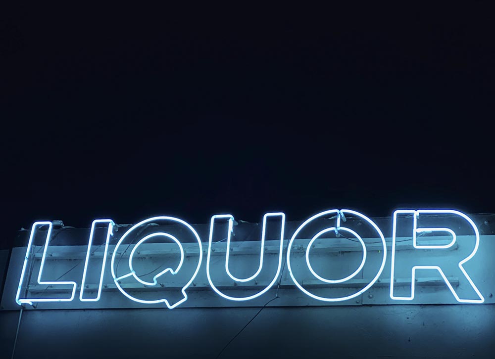 A blue neon "Liquor" sign in the dark