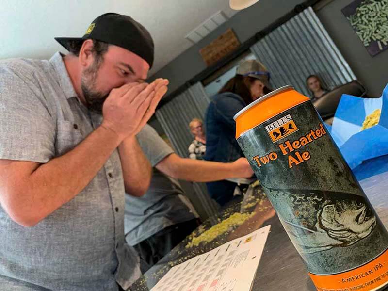A brewer from Bells' Brewery sniff testing hops with a can of Two Hearted Ale in the foreground