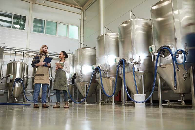 A male and female brewer take a break after creating a new batch using BeerXML recipes