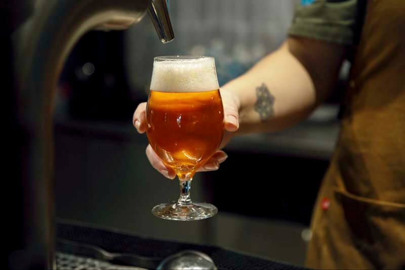 A close up photo of a bartended serving a non-alcoholic beer directly from a tap
