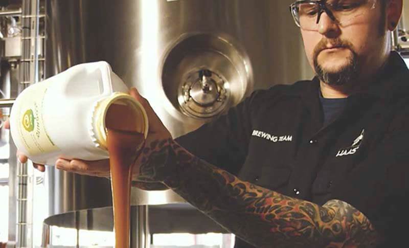 A brewer pouring Incognito hops into a craft brewery tank