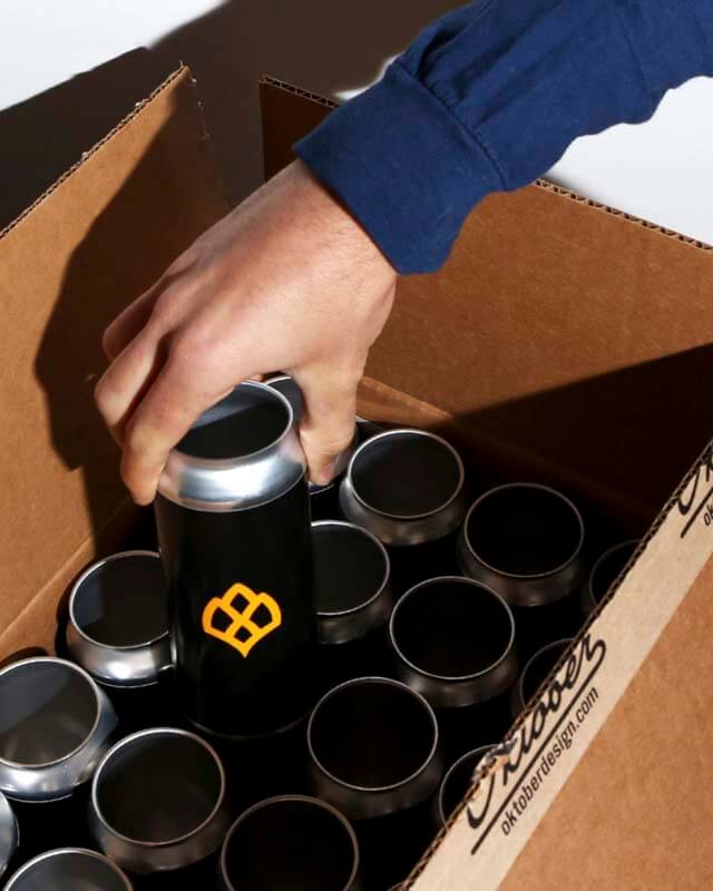 Close up of a hand pulling unseamed craft beer cans from a cardboard box