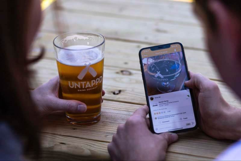 A couple checking in a beer at a brewery using the Untappd app