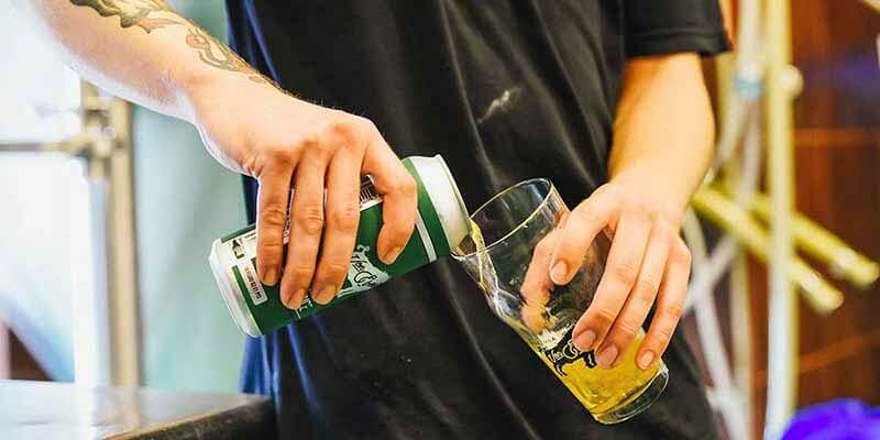 A photo of a brewer pouring a can of Von Ebert Vapor Machine craft beer from a can into a glass
