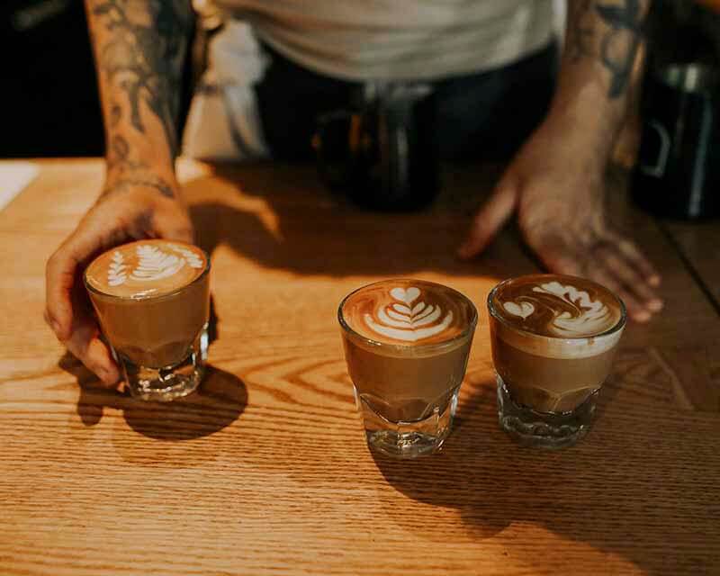 An aerial shot of coffee in glasses featuring unique latte art being served by a bartender at Trace Brewing