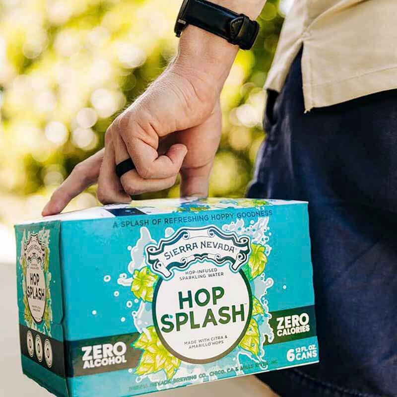 A close up photo of a person carrying a six-pack of Hop Splash hop water