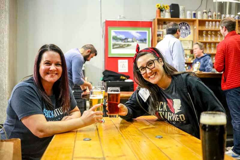 Two women toasting craft beers in glasses at a Texas Brewers Guild event