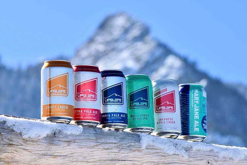 A photo of the Upslope Brewing Company variety of flavors and drinks in front of a snowy mountainscape