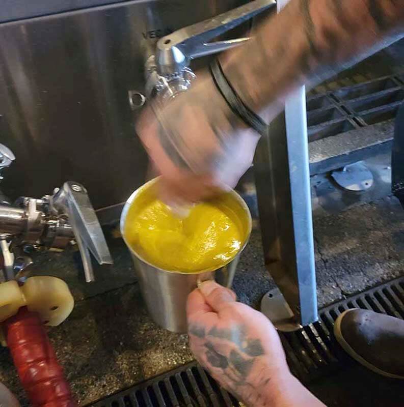Up close photo of Blewett Brewing Company brewer adding HOPSAUCE to kettle or whirlpool