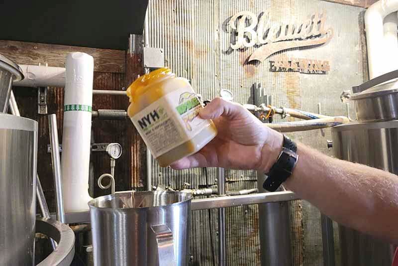 An up close photo of a brewer at Blewett Brewing Company using a container of HOPSAUCE