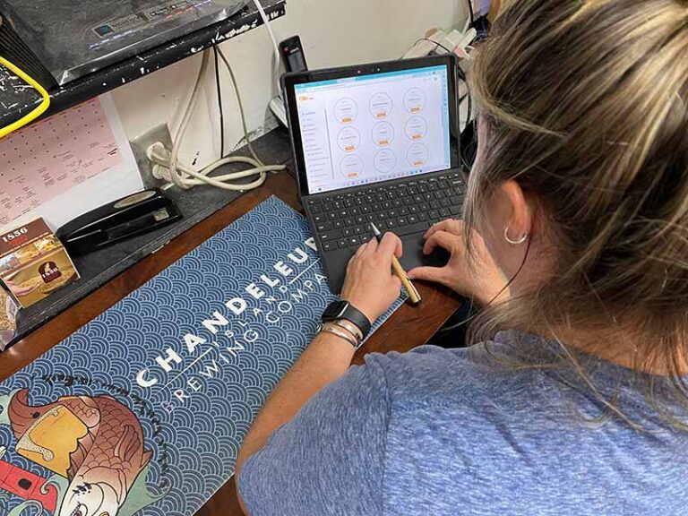 A photo of Chandy Island brewer Katie Baimbridge using Ollie on her laptop at Chandy Island Brewing