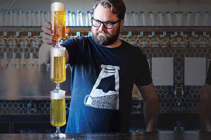 Our Mutual Friend (OMF) head brewer, Jan Chadowski stacking glasses of beer at the bar