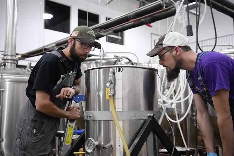 Brewers at Checkerspot Brewing make a new brew kettle into place