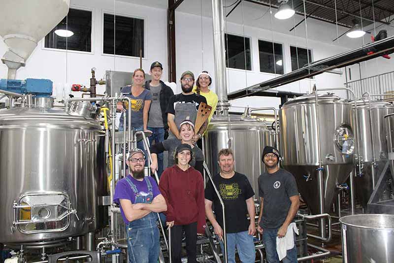 The team at Checkerspot Brewing posing for a photo in front of their new brew kettles