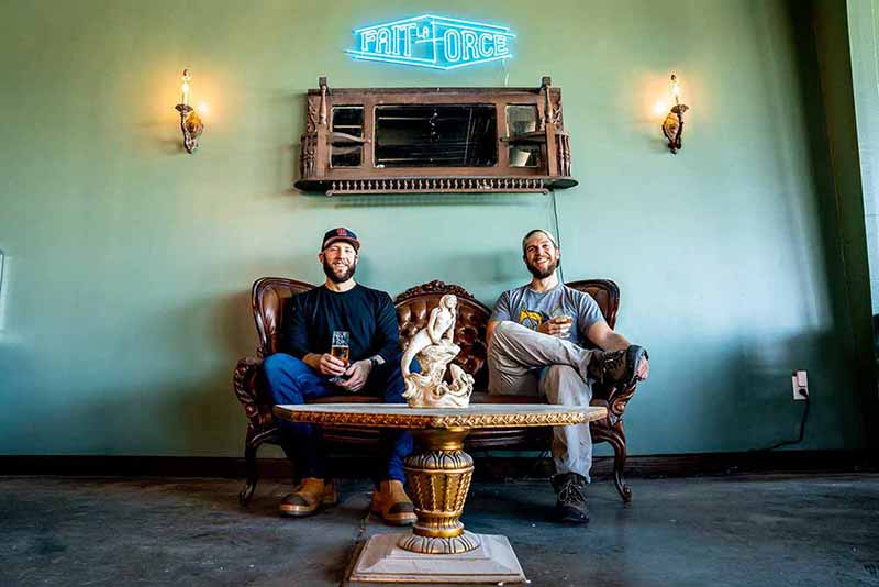 Fait La Force Brewing co-founders Parker Loudermilk and Zachary Sowada sit on a couch