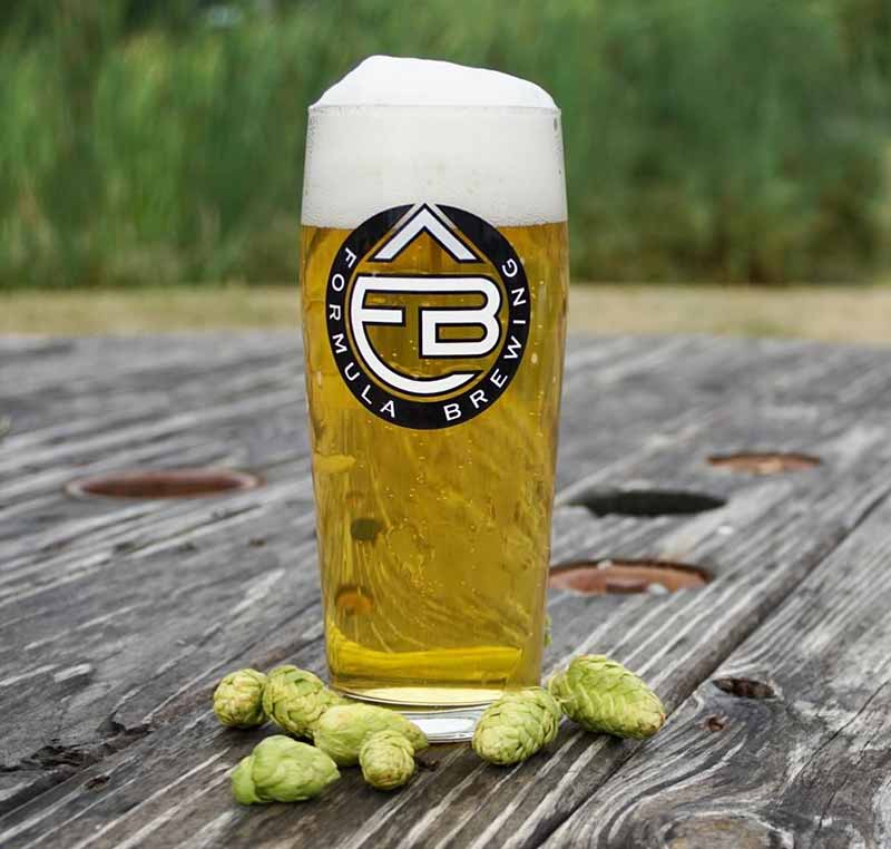 A glass of Formula Brewing fresh hop beer in a promotional photo shot outside