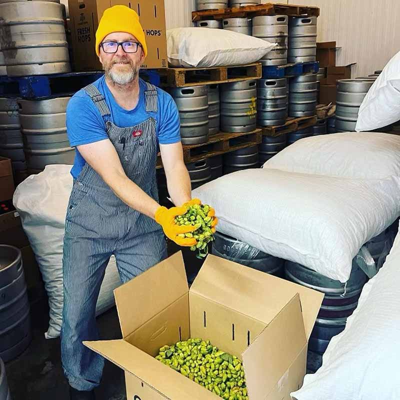A brewer at Formula Beers unpacks and holds a box of fresh hops