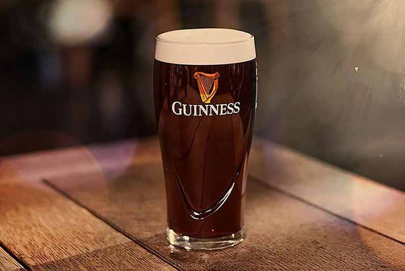 A pint of Guiness Draught Dry Irish Stout on a wooden table