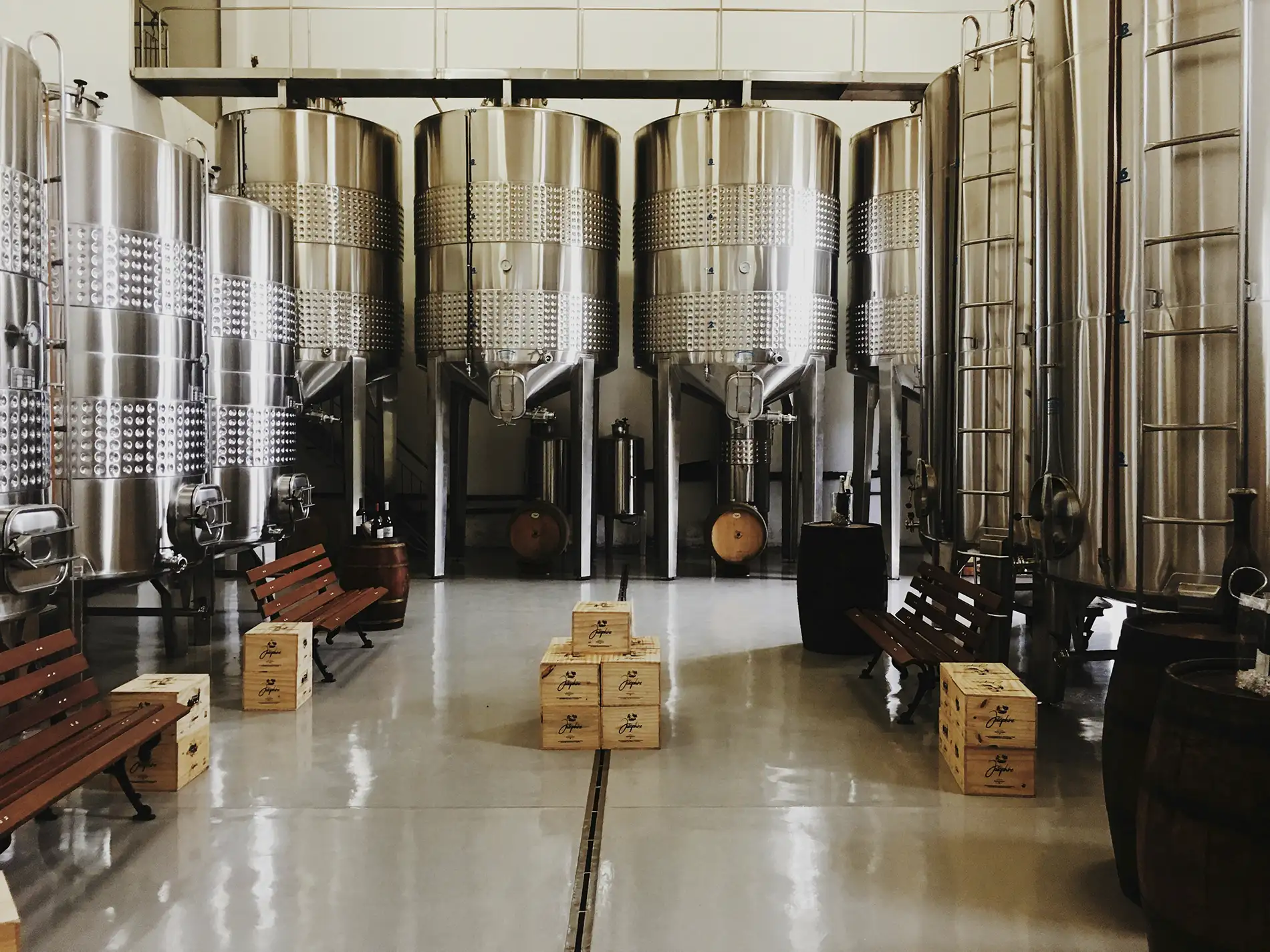 A photo of a brewery production floor with tanks and ingredient boxes