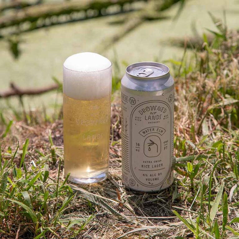 A rice lager in a can and pint glass from The Drowned Lands Brewery
